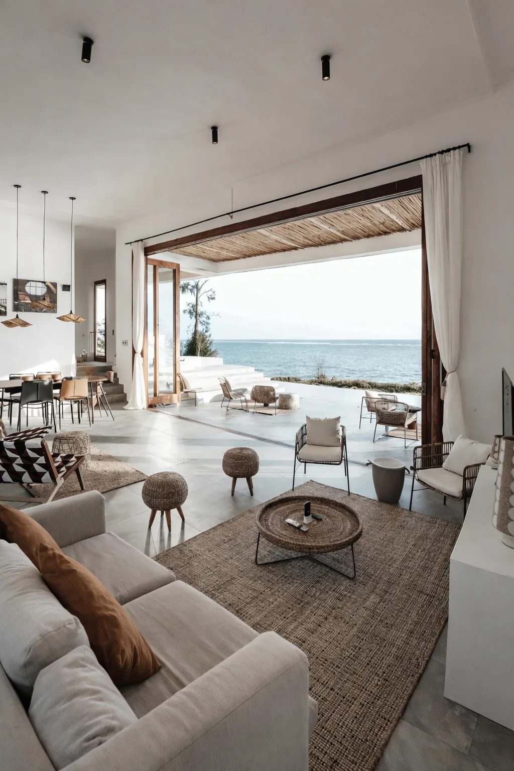 Séjour ouvert sur la mer, mobilier clair et grandes baies vitrées